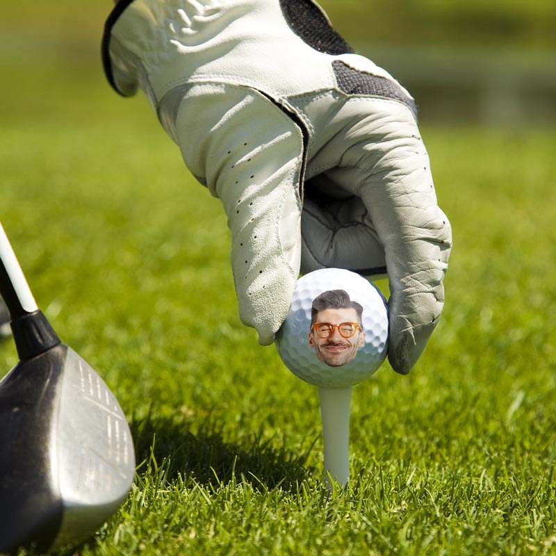 Personalized golf ball on tee with custom face and 'If found, return to this guy' message, perfect gift.